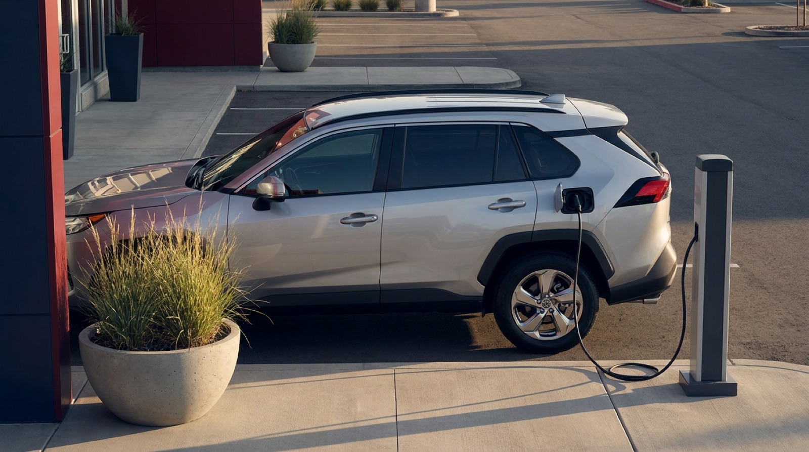 A hybrid crossover charging in a dealership bay, cable plugged in, morning sun across the hood